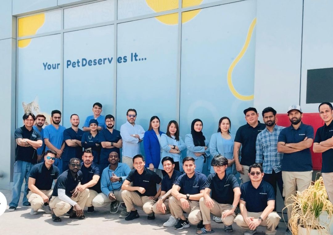 The Pet Pavilion team in front of the “Your Pet Deserves It” wall at the clinic in Mussafah